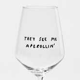 Das Weinglas "They See Me Aperollin'" von Johanna Schwarzer aus dem Hause Selekkt zeigt eine verspielte schwarze Handschrift auf einem klaren, spülmaschinengeeigneten Glas - witzig und praktisch zugleich, dargestellt vor einem schlichten weißen Hintergrund.