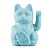 Die Lucky Cat - Winkekatze hellblau von Donkey Products ist eine hellblaue Maneki Neko-Figur mit erhobener rechter Pfote, vereinfachten Gesichtszügen und einer ovalen Tafel mit geprägten Markierungen.