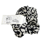 Der Leo Scrunchie von Ella & Monster ist ein schwarz-weiß gemustertes Haaraccessoire mit einem Markenanhänger - ein Blickfang für jeden Stil.