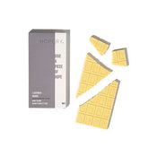 Ein Riegel Hopery Lavender Orange - Badeschokolade wird teilweise in Stücke gebrochen und neben seiner Verpackung auf weißem Hintergrund ausgestellt.