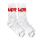 Ein Paar weiße Crew Navucko Socken "Amore", made in Germany, mit rotem Schriftzug "AMORE" auf der Oberseite.