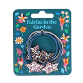 Der "Glitzerstern" Haarbänder (4er Set) von Rex London zeigt zwei blaue und zwei silberne sternförmige Bänder auf einer Karte mit Feen- und Blumenmotiven, beschriftet mit "Fairies in the Garden" - ein bezauberndes Geschenk.