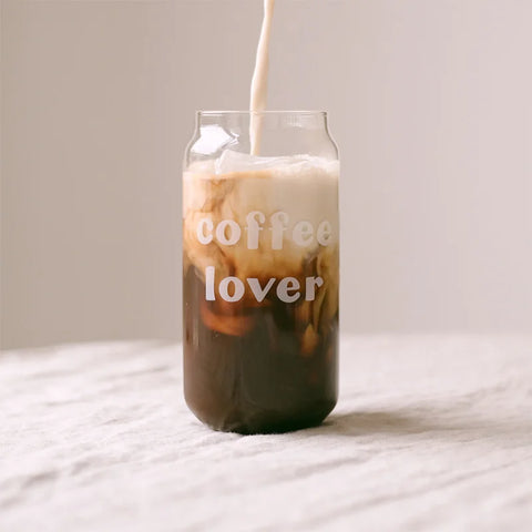 Das Eulenschnitt Hohes Trinkglas "Coffee Lover" ist mit Milch gefüllt, die auf einer hellen Oberfläche in Eiskaffee schwappt - ideal für den Genuss Ihrer Lieblings-Sommer-Cocktails oder -Getränke.