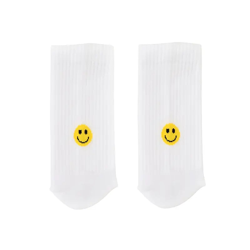 Die Socken "Smiley" gelb von Eulenschnitt aus weißer Bio-Baumwolle zeigen mittig auf jeder Socke einen kleinen gelben Smiley. Sie sind flach auf schlichtem weißen Hintergrund arrangiert.
