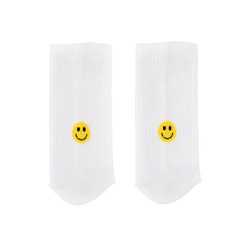 Die Socken "Smiley" gelb von Eulenschnitt aus weißer Bio-Baumwolle zeigen mittig auf jeder Socke einen kleinen gelben Smiley. Sie sind flach auf schlichtem weißen Hintergrund arrangiert.