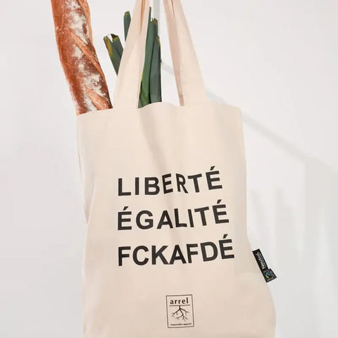 Die Arrell FCKAFDÉ Premium Tote Bag - Nature & Black mit schwarzem Text hält ein Baguette und grünes Gemüse vor einem schlichten weißen Hintergrund.