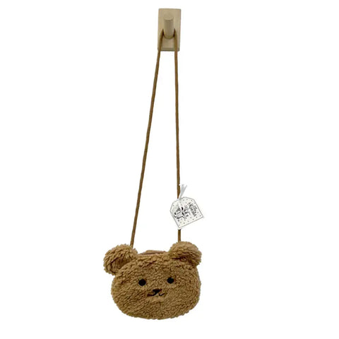 Die Tasche "Teddy" Kunstfell braun von Ella & Monster ist eine kleine braune Tasche in Form eines Bärengesichts, mit runden Ohren und einem langen Riemen - ideal als niedliches Kinder-Accessoire. Am Gurt ist ein weißer Anhänger befestigt.