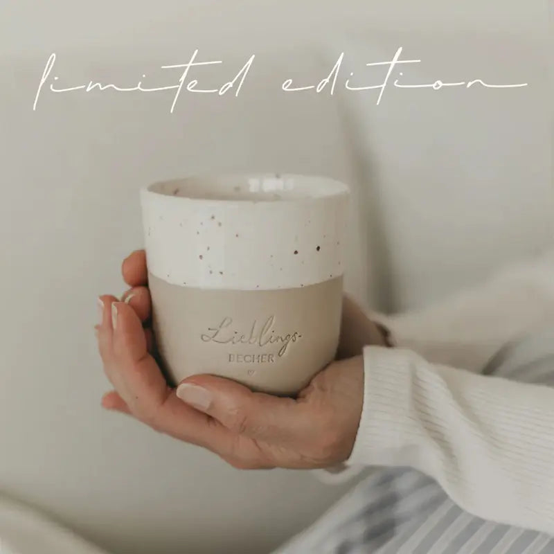 Eine Person hält den Eulenschnitt Limitierter Becher "Lieblingsbecher" aus Steingut. "Limited Edition" steht kursiv darüber, und der handgemachte Portugal-Becher erscheint vor einem weichen, neutralen Hintergrund.