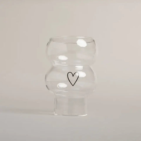 Die Vase Double Bubble Glas "Herz" von Eulenschnitt besticht durch ihr klares, geschwungenes Design mit einem schlichten schwarzen Herz auf der Vorderseite - ein stilvolles Geschenk für jeden Anlass.