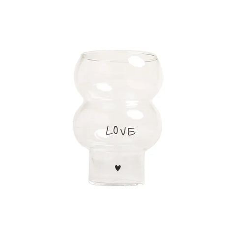 Die Vase Double Bubble Glas "Love" von Eulenschnitt hat eine klare, runde, gewellte Form mit dem Schriftzug "LOVE" und einem kleinen schwarzen Herz auf der Vorderseite, das sich von einem weißen Hintergrund abhebt.