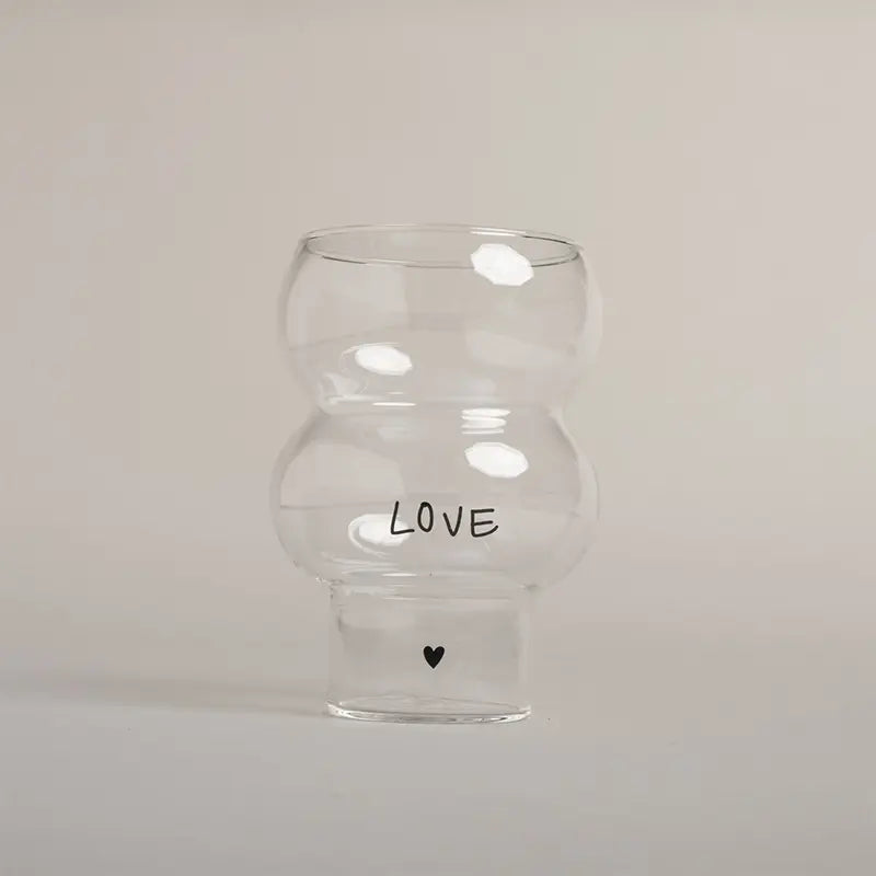 Die Eulenschnitt Double Bubble Glas "Love" Vase hat eine einzigartige Form, zeigt "LOVE" in schwarzen Buchstaben mit einem kleinen schwarzen Herz darunter und ist vor einem schlichten hellen Hintergrund fotografiert.