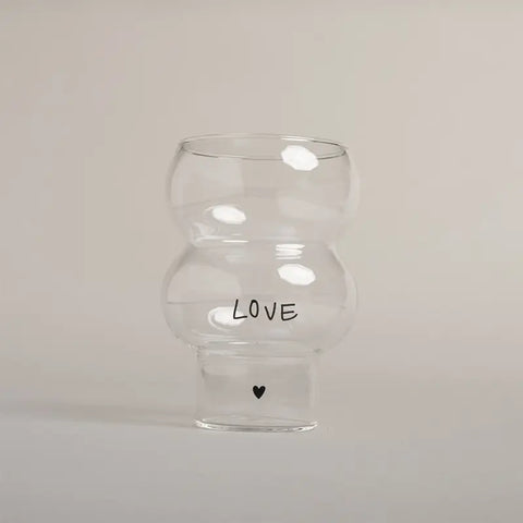 Die Eulenschnitt Double Bubble Glas "Love" Vase hat eine einzigartige Form, zeigt "LOVE" in schwarzen Buchstaben mit einem kleinen schwarzen Herz darunter und ist vor einem schlichten hellen Hintergrund fotografiert.