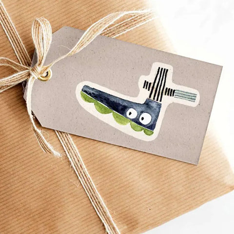 Ein in braunes Papier verpacktes und mit weißer Schnur verschnürtes Geschenk mit einem Halfbird Stickerbogen - Zahlen (2 Bögen) Geschenkanhänger, der mit skurrilen Zahlen und verspielten Motiven verziert ist.