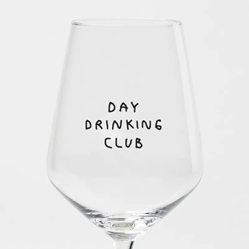 Das "Day Drinking Club" Weinglas von Johanna Schwarzer aus dem Hause Selekkt zeigt einen verspielten, handgeschriebenen schwarzen Text auf einer klaren Schale mit Siebdruck vor einem schlichten weißen Hintergrund - ideal für Fans von exklusiven Weingläsern.