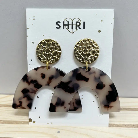 Ein Paar Shiri Ohrringe "Berlin" mit goldenen, strukturierten, runden Ohrsteckern und großen, geschwungenen, schildpattgemusterten Acetat-Anhängern, die auf einer weißen Karte mit der Aufschrift SHIRI und einem Herz über dem Text präsentiert werden.