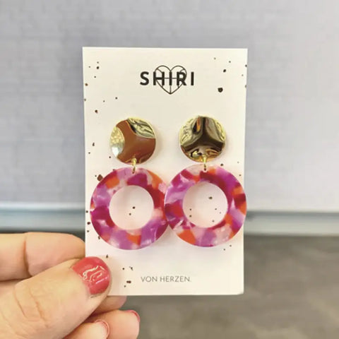 Eine Hand hält eine Karte mit der Aufschrift SHIRI ♥ VON HERZEN mit bunten Ohrringen "Team Bold" - jeweils mit einem glänzenden Goldknopf und einem großen marmorierten Reifen, perfekt als Statement-Schmuck aus Hannover.