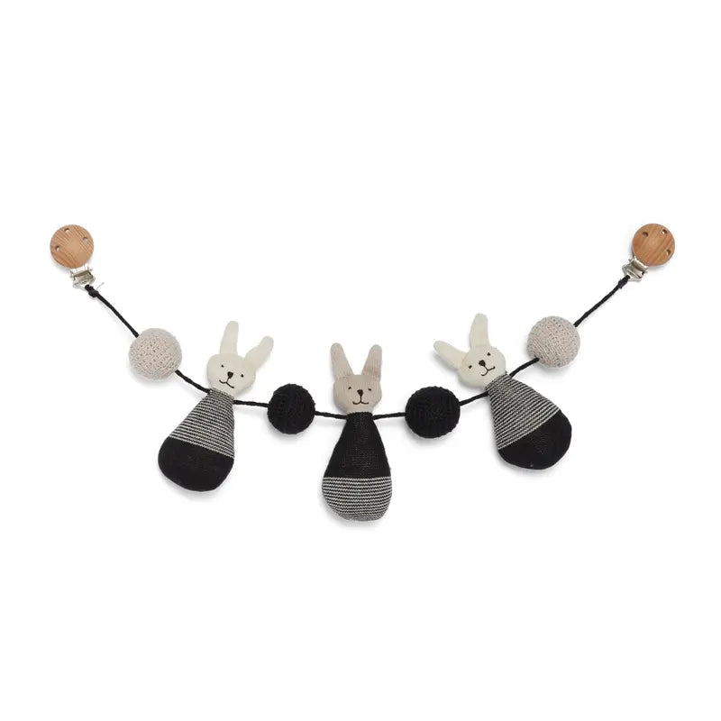 Die Kinderwagenkette "Häschen" Baumwolle von Sophie Home besteht aus drei gestrickten Hasengesichtern mit schwarz-grau gestreiften Körpern sowie schwarzen und beigen Bommeln an einer schwarzen Kordel mit Holzclips - ideal als Babyzubehör.