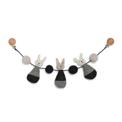 Die Kinderwagenkette "Häschen" Baumwolle von Sophie Home besteht aus drei gestrickten Hasengesichtern mit schwarz-grau gestreiften Körpern sowie schwarzen und beigen Bommeln an einer schwarzen Kordel mit Holzclips - ideal als Babyzubehör.