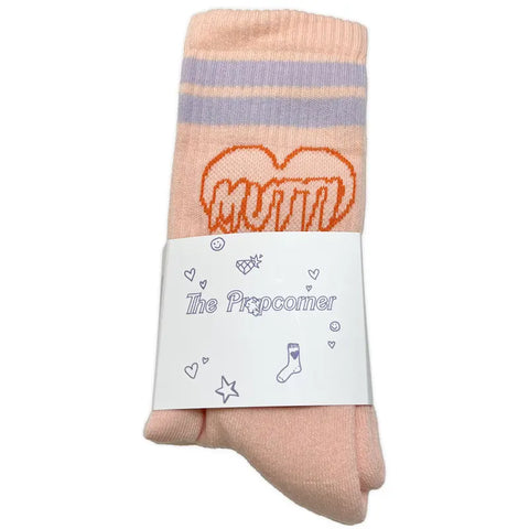 Die Mutti Socken (Pfirsich) von Propcorner sind rosa Sportsocken mit lila Streifen und einem orangefarbenen Herz mit der Aufschrift "MUTTI", die aus Bio-Baumwolle bestehen und mit einem weißen Etikett mit kleinen dekorativen Symbolen versehen sind.