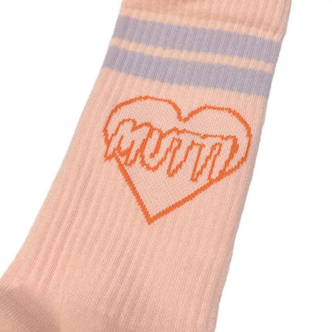 Eine Nahaufnahme der Mutti Socken (Pfirsich) von The Propcorner, hergestellt aus Bio-Baumwolle, mit zwei hellvioletten Streifen und einem orangefarbenen Herz, auf dem in fetten orangefarbenen Buchstaben MUTTI steht. Limitierte Auflage.