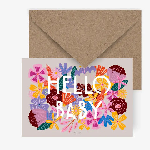 Die Postkarte "Bloomy Baby" von Typealive zeigt den fetten weißen Text "HELLO BABY", umgeben von bunten, illustrierten Blumen, und wird mit einem Umschlag aus braunem Kraftpapier geliefert.
