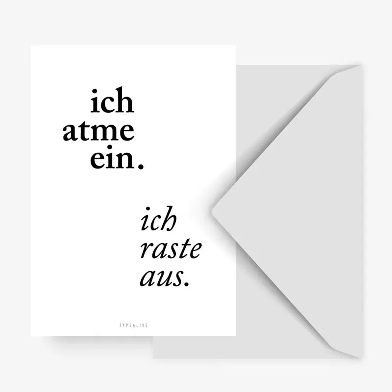 Die Postkarte "Ich atme ein" von Typealive zeigt deutschen Text - "ich atme ein." in Fettdruck (oben links) und "ich raste aus." in Kursivschrift (unten rechts) - auf weißem Grund, mit einem stilvollen grauen Umschlag, der teilweise dahinter sichtbar ist.